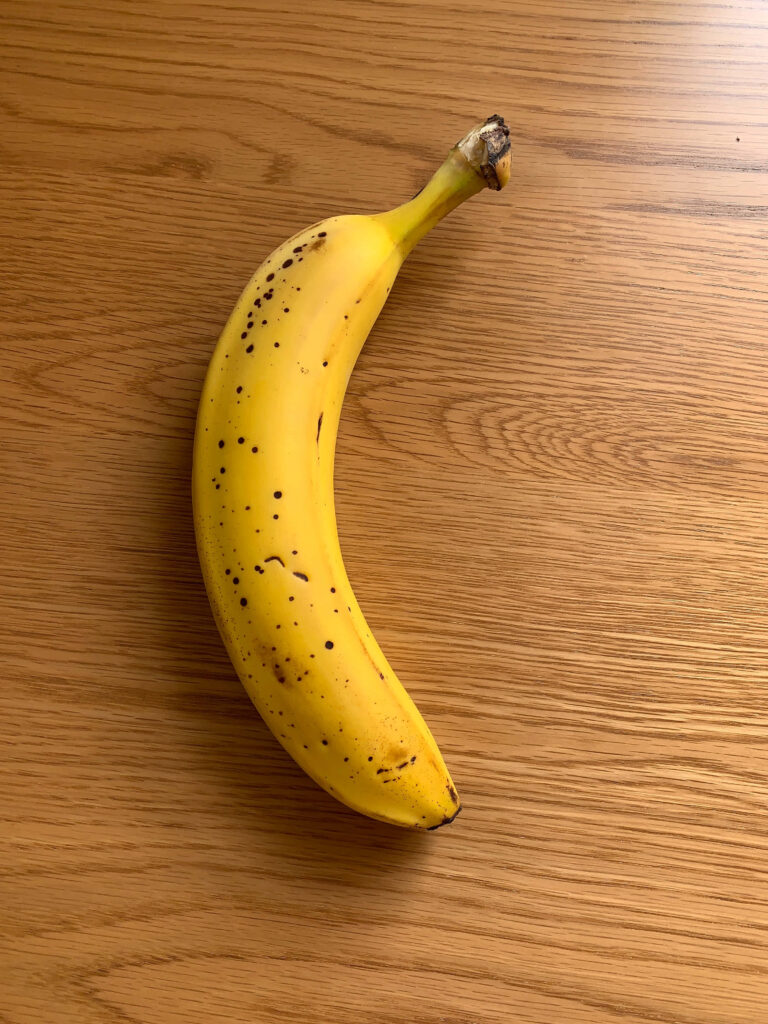 Ripe yellow banana on smooth wooden surface fresh vibrant fruit wallpaper background