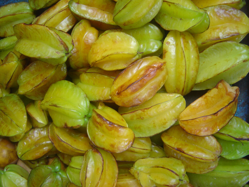Close-up of fresh glossy yellow green starfruit carambola with ridged shape tropical wallpaper
