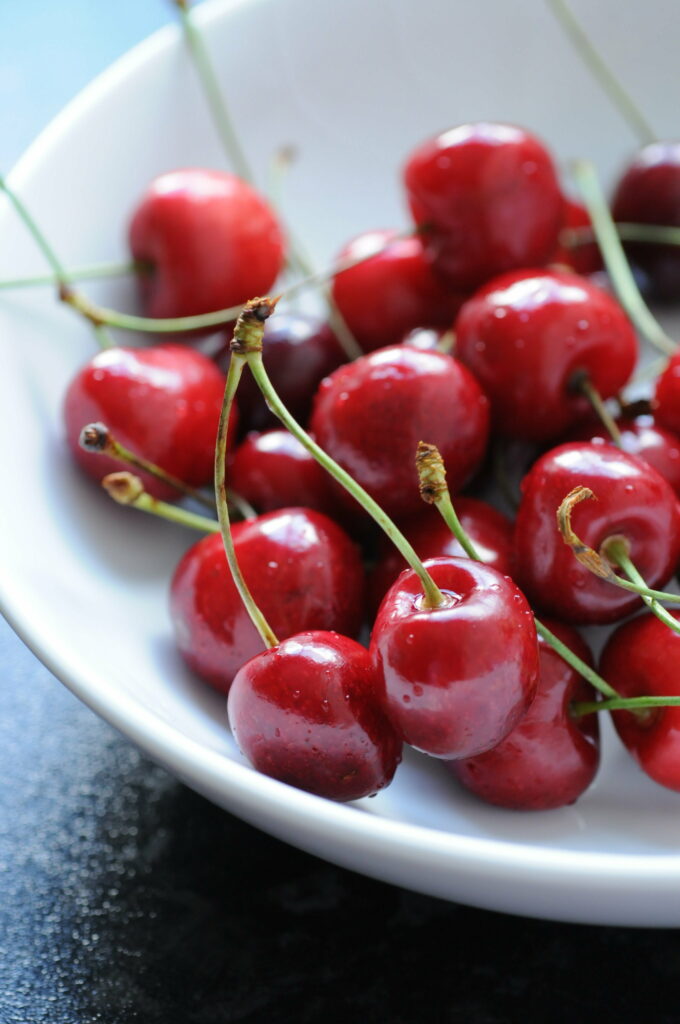 Vibrant Cherries in White Bowl: Refreshing Water Droplet Wallpaper