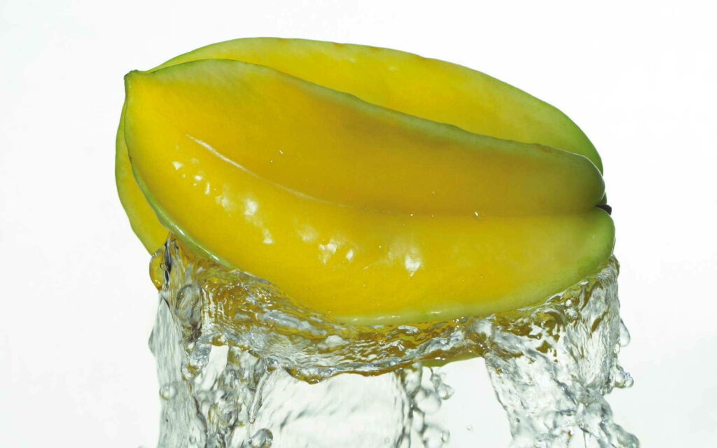 Fresh yellow star fruit splashed with water on bright background vibrant refreshing wallpaper