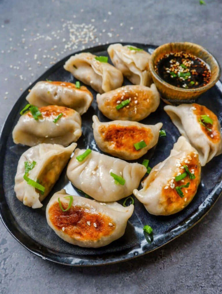 Fresh Dumplings Display on Black Platter with Dipping Sauce Wallpaper