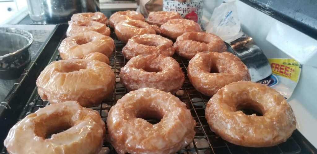 Freshly glazed golden brown donuts cooling on wire rack in cozy home kitchen wallpaper background
