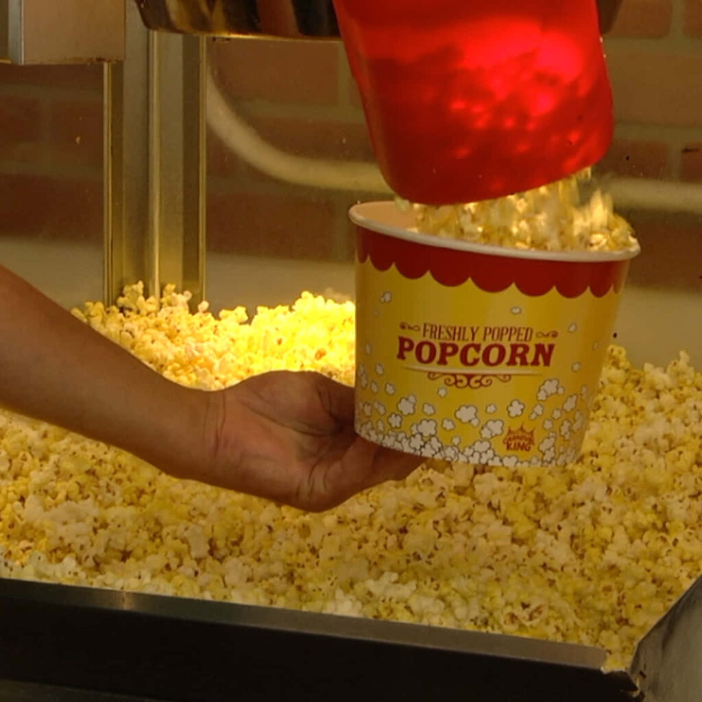 Freshly Popped Popcorn in Yellow Bucket Near Popcorn Machine Wallpaper