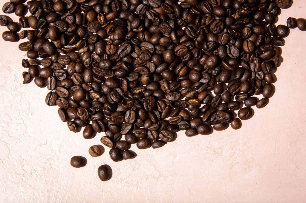 Close-up of freshly roasted dark coffee beans on textured surface with natural warm lighting Wallpaper