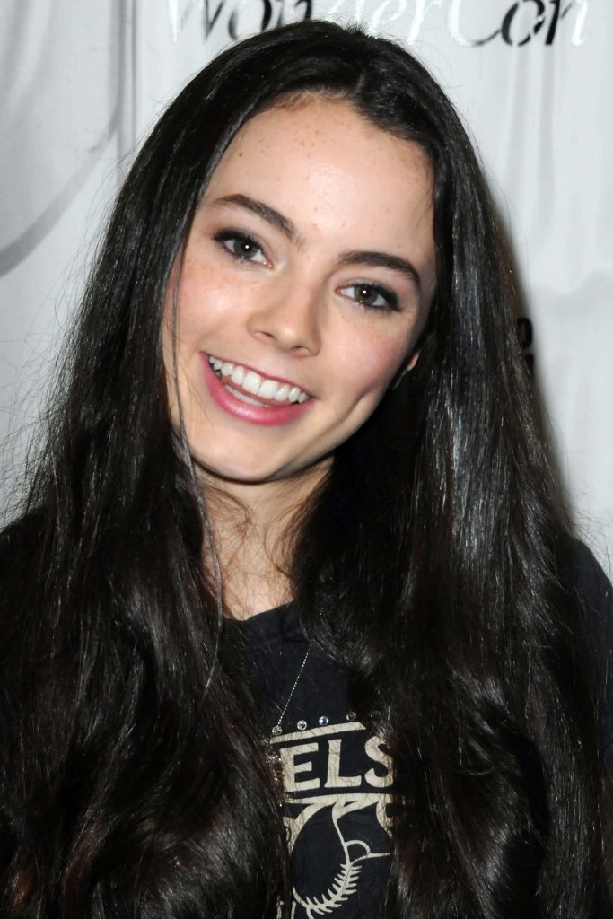 Freya Tingley smiling at WonderCon wearing black t-shirt with wavy dark hair backdrop Wallpaper