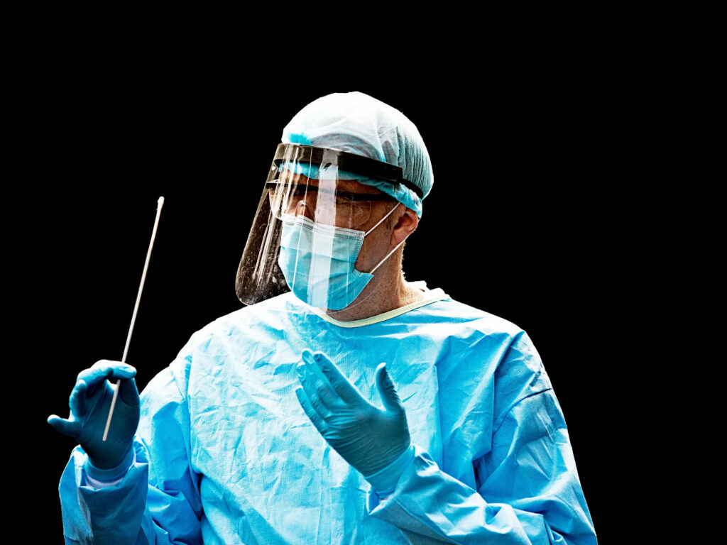 Doctor in full protective gear holding medical swab on black background frontline healthcare worker Wallpaper