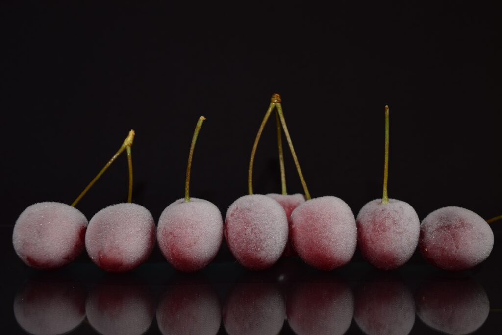 Frozen Cherries Wallpaper: Frosted Fruit on Dark Reflective Background