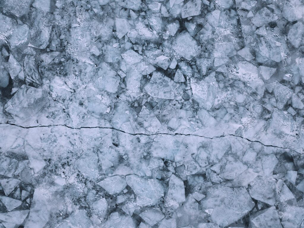 Frozen ice wallpaper with jagged crystals and horizontal crack in icy blue and white tones