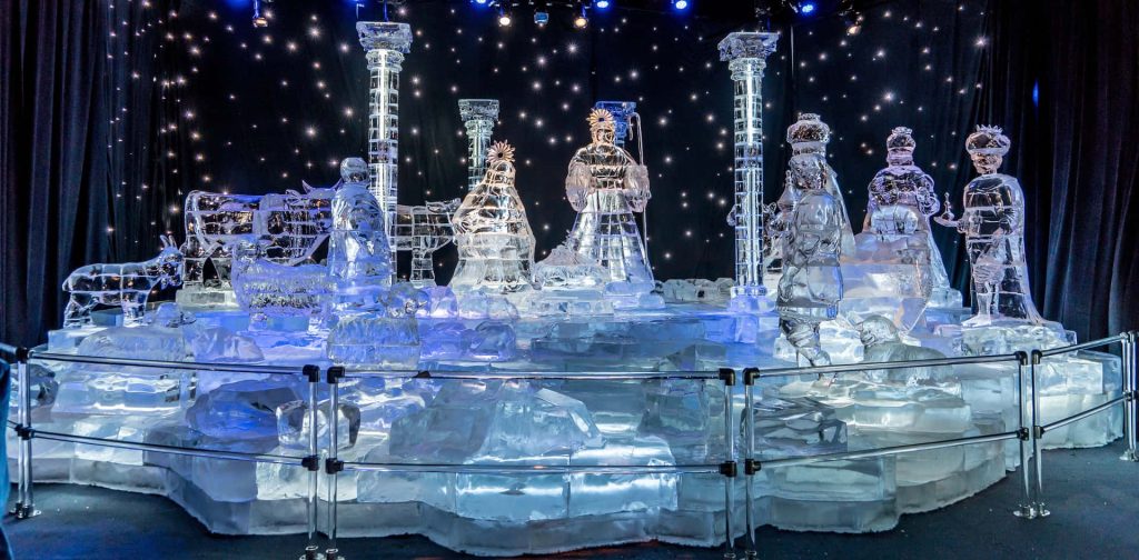 Intricate ice Nativity scene glowing blue with holy family wise men animals starry winter backdrop Wallpaper