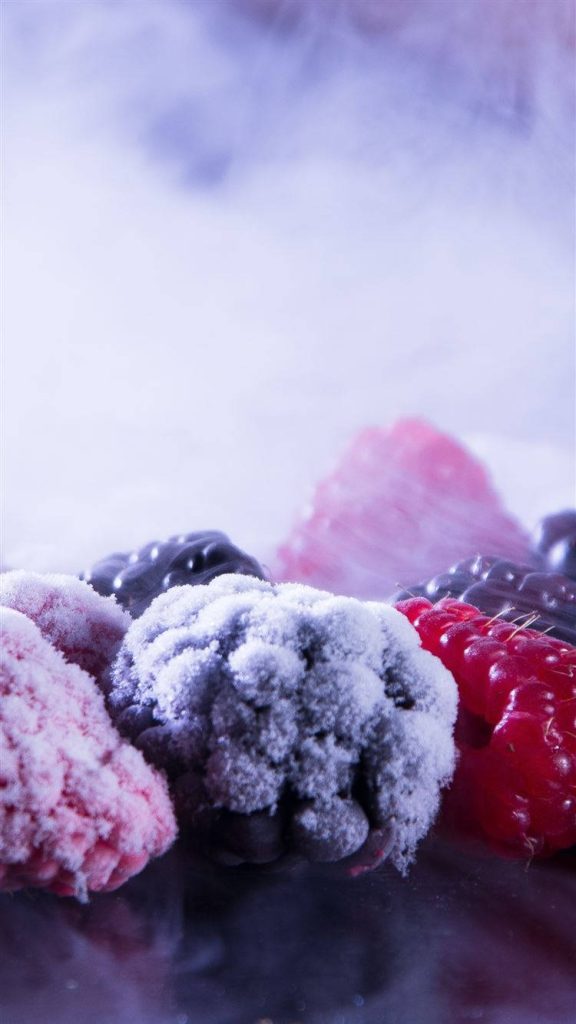 Close-up of frozen red raspberries and blackberries with sparkling frost on cool background wallpaper