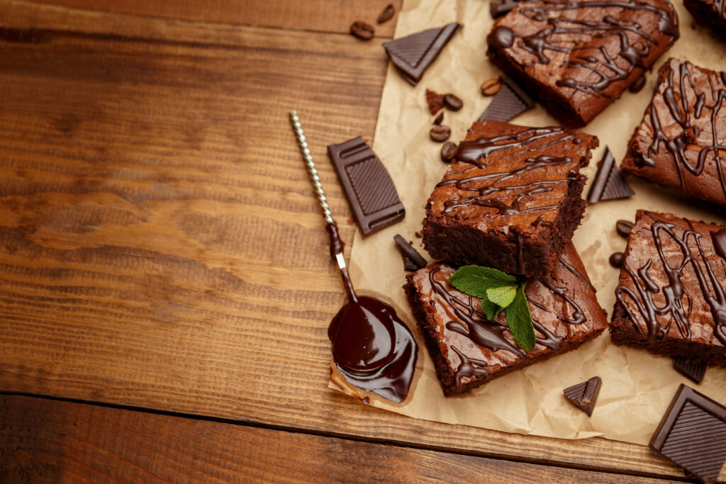 Fudgy brownies with chocolate drizzle dark chocolate pieces and coffee beans on rustic parchment Wallpaper