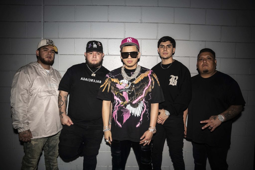 Fuerza Regida band members in streetwear pose against grey wall urban music wallpaper background