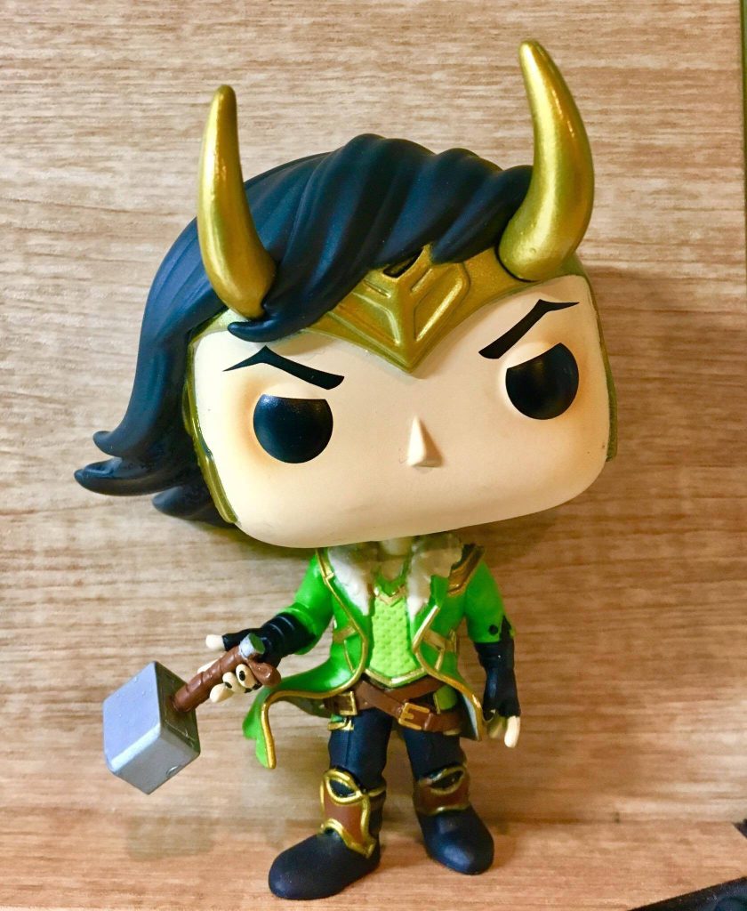 Funko Pop Loki vinyl figure in gold horned helmet and green armor with hammer on wood background Wallpaper