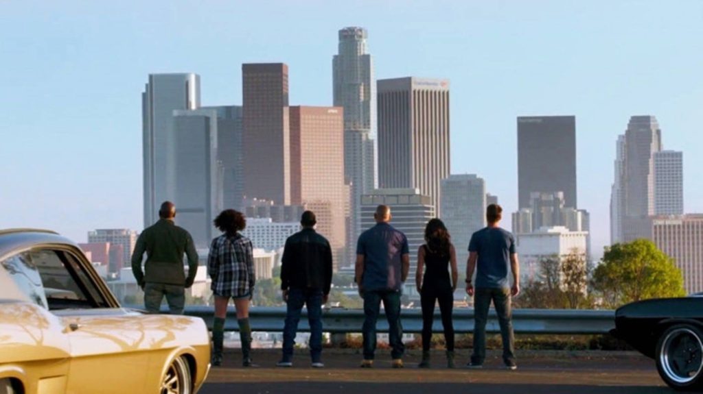 Furious Seven crew with classic muscle cars overlooking sunlit Los Angeles skyline wallpaper