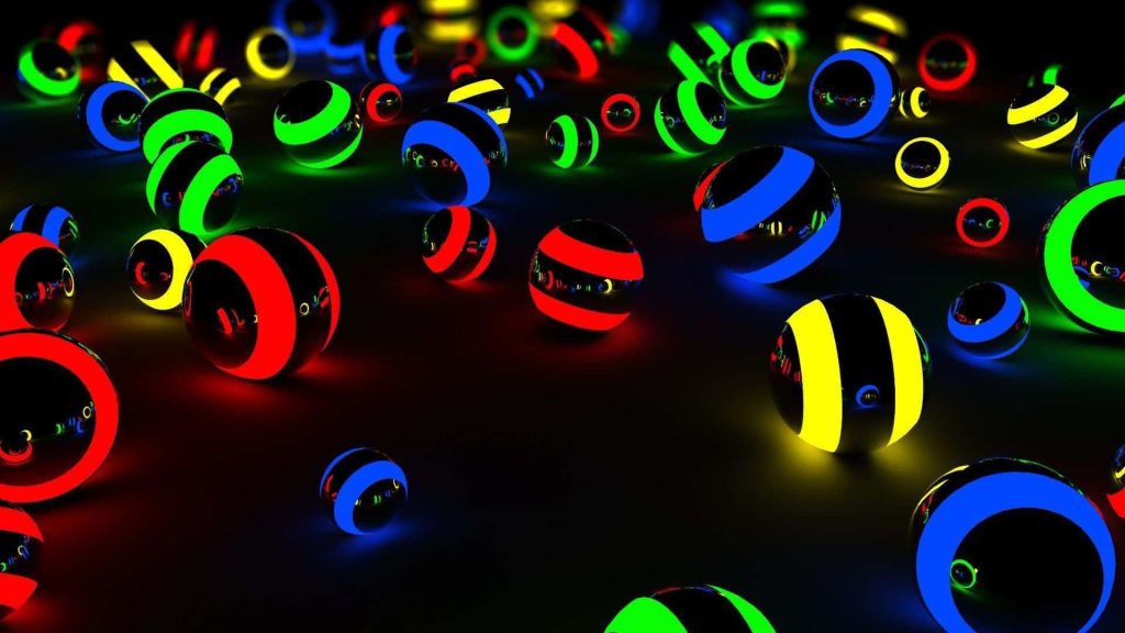 Glossy dark spheres with glowing neon rings in red blue green and yellow on black background wallpaper