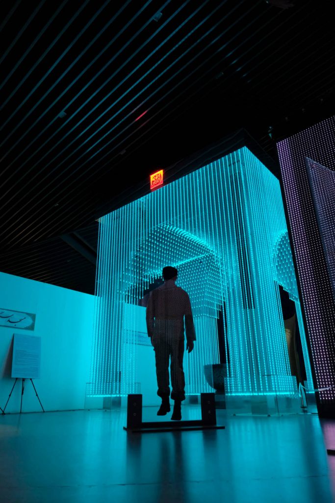 Silhouette against futuristic cyan LED light archway in immersive modern art gallery wallpaper background
