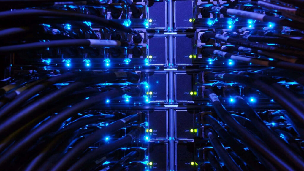 Close-up of Ethernet cables plugged into server rack with blue and green LED lights networking Wallpaper