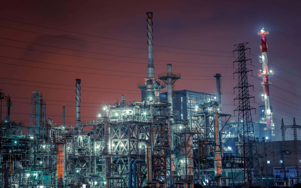Night industrial complex wallpaper with illuminated smokestacks metal framework and power lines