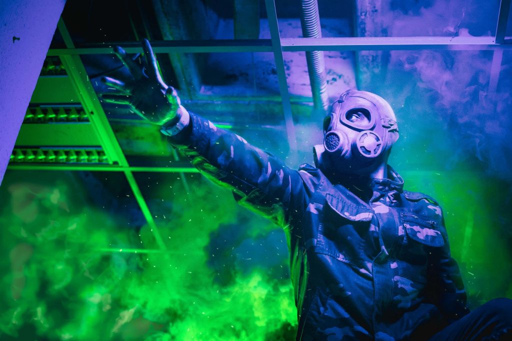 Futuristic survivor in gas mask with neon green purple smoke industrial post-apocalyptic wallpaper