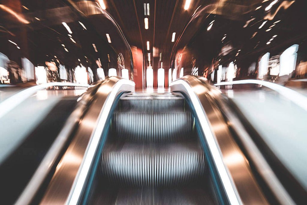 Low-angle view of metallic escalator steps with glowing rails and cinematic motion blur wallpaper