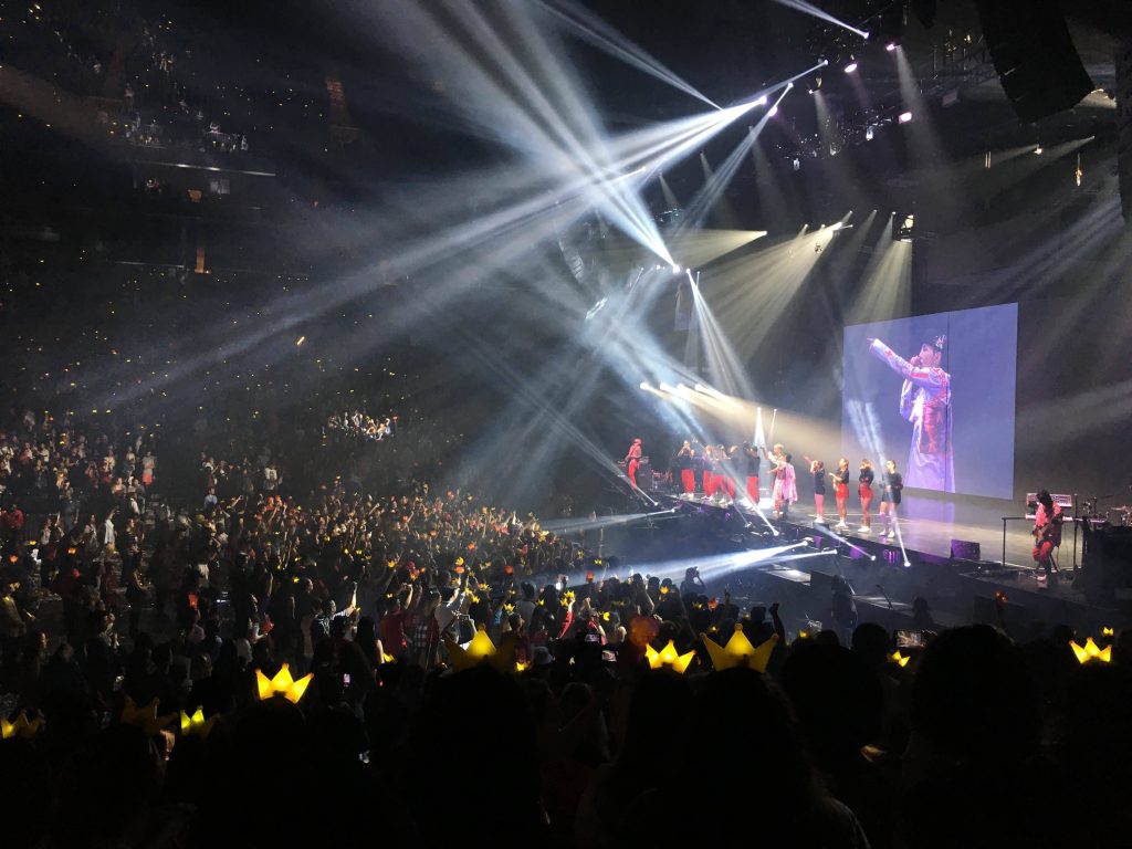G-Dragon concert packed arena with yellow crown lightsticks glowing under spotlights wallpaper