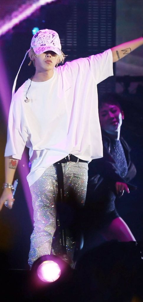 G-Dragon live performance in white tee and shimmering trousers under purple stage lights wallpaper