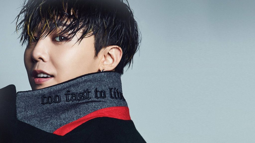 Sharp studio portrait of K-pop legend G-Dragon in black jacket with highlighted hair on grey background Wallpaper