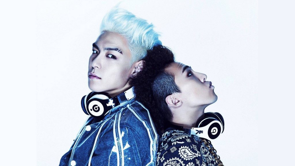 K-pop legends G-Dragon and TOP back-to-back in edgy fashion with headphones white background Wallpaper