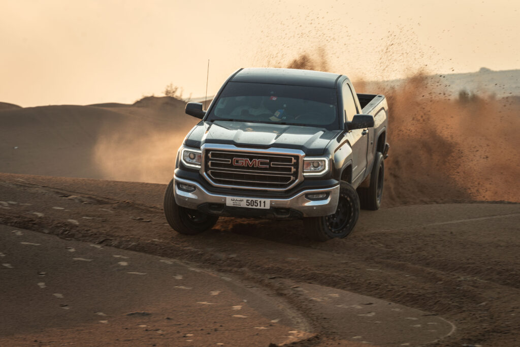 Dynamic GMC Pickup Truck Driving Through Sandy Terrain Wallpaper