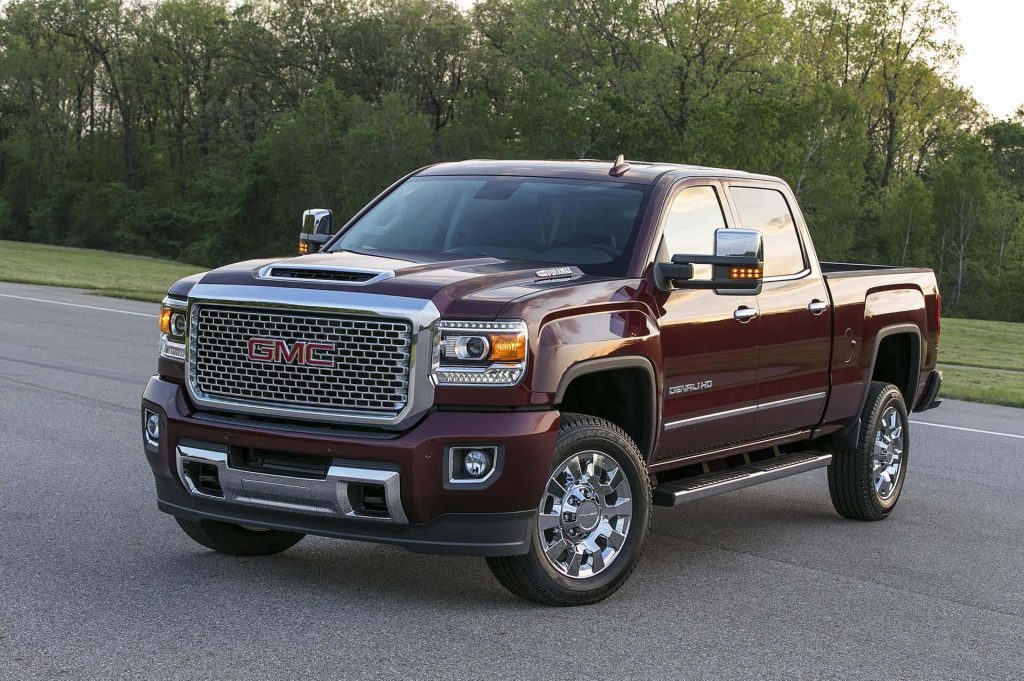 Deep maroon GMC Sierra Denali HD truck with chrome grille Duramax badge on scenic road wallpaper