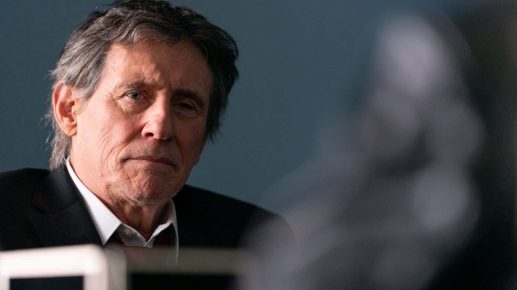 Gabriel Byrne intense gaze portrait in dark suit white shirt moody studio lighting background Wallpaper
