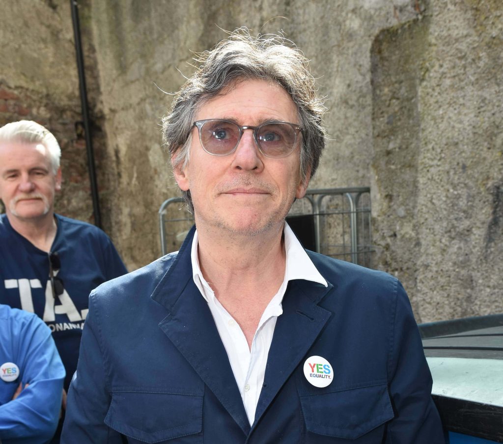 Actor Gabriel Byrne in navy jacket with Yes Equality pin outdoor portrait stone wall background Wallpaper