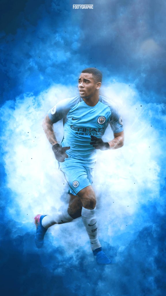 Manchester City striker Gabriel Jesus in sky-blue kit running with swirling blue smoke background Wallpaper