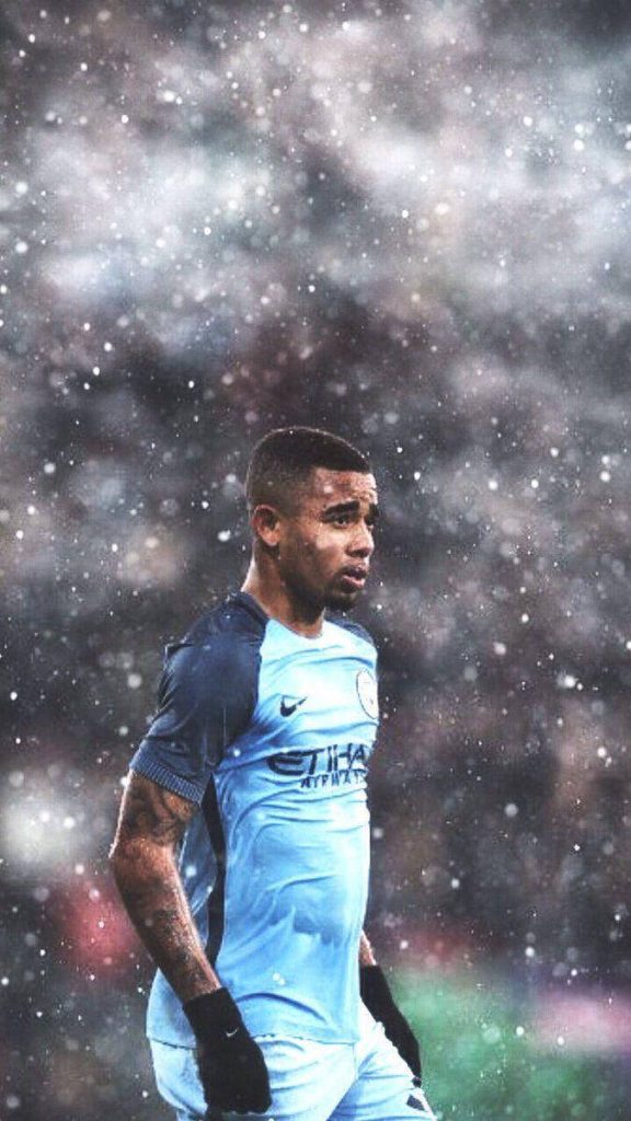 Manchester City Gabriel Jesus in light blue kit with glowing particles dark stadium background Wallpaper