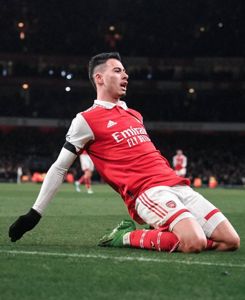 Gabriel Martinelli Arsenal goal celebration sliding on knees in red and white kit stadium lights Wallpaper