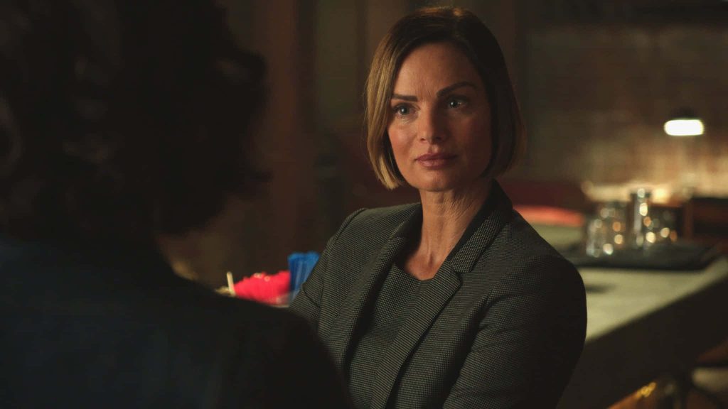 Cinematic portrait of Gabrielle Anwar in sleek bob and grey blazer in warm dimly lit room Wallpaper