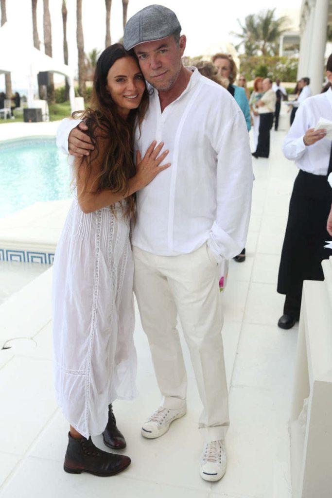 Gabrielle Anwar and Shareef Malnik in white by sunny poolside terrace embracing candidly Wallpaper