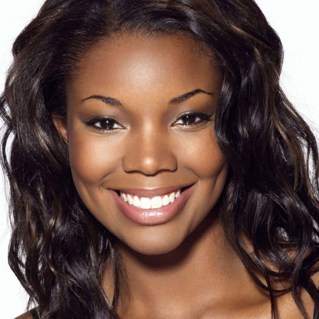 Gabrielle Union smiling in black off shoulder dress with wavy dark hair on white background Wallpaper