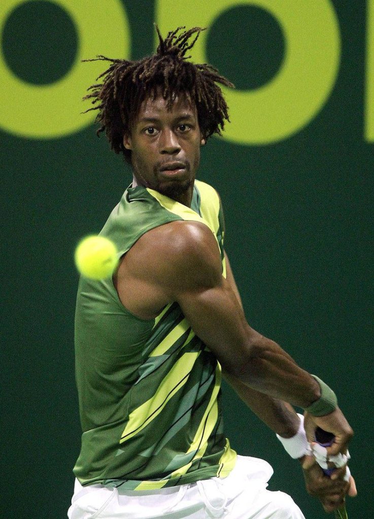 Gaël Monfils powerful backhand tennis action in green yellow kit on vibrant court background Wallpaper