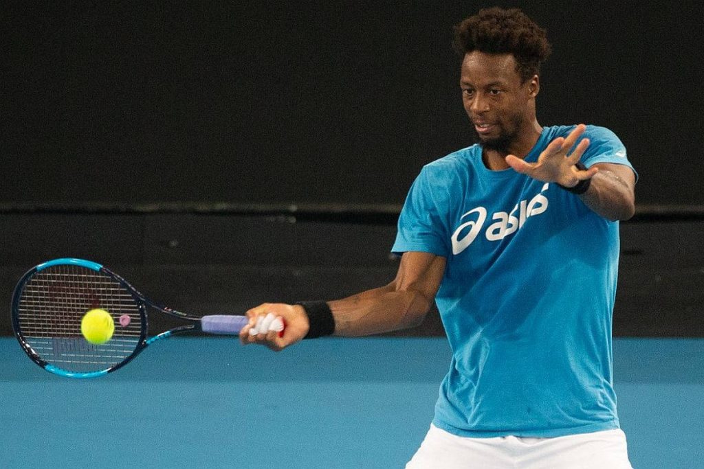 Tennis star Gaël Monfils mid-swing in blue Asics shirt on blue hard court action wallpaper
