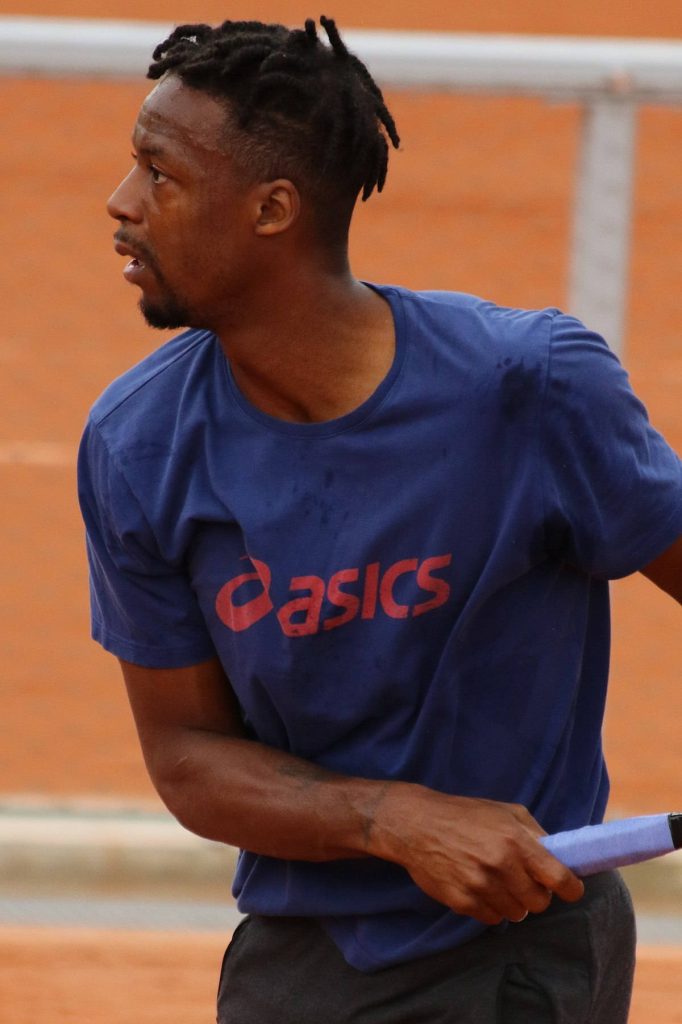 Gaël Monfils in blue Asics on orange clay court showcasing focus and athleticism tennis action Wallpaper