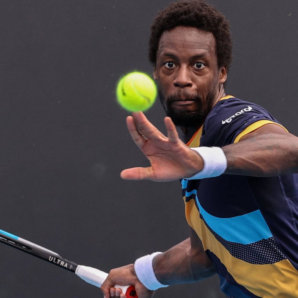 Gaël Monfils intense tennis action with Wilson Ultra racquet hitting yellow ball on dark court Wallpaper