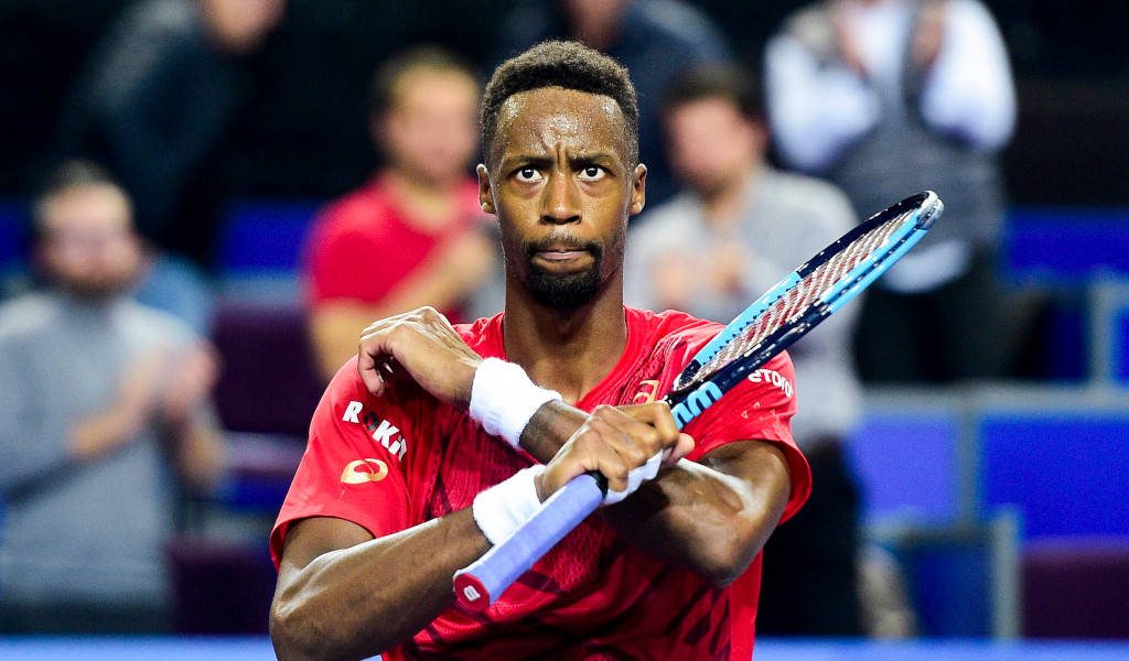 Tennis star Gaël Monfils in red shirt with racket stands intense stadium wallpaper background