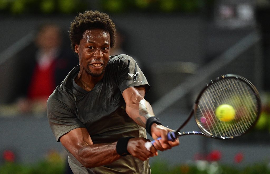 Gaël Monfils mid-swing hitting yellow tennis ball intense focus stadium lighting wallpaper
