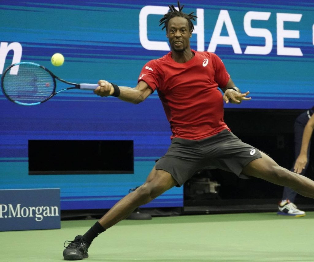 Gaël Monfils mid-swing in red shirt on hard court US Open tennis action wallpaper background