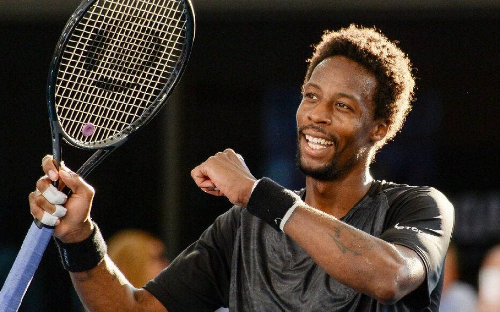 Gaël Monfils celebrating a tennis win pumping fist with racket under bright stadium lights Wallpaper