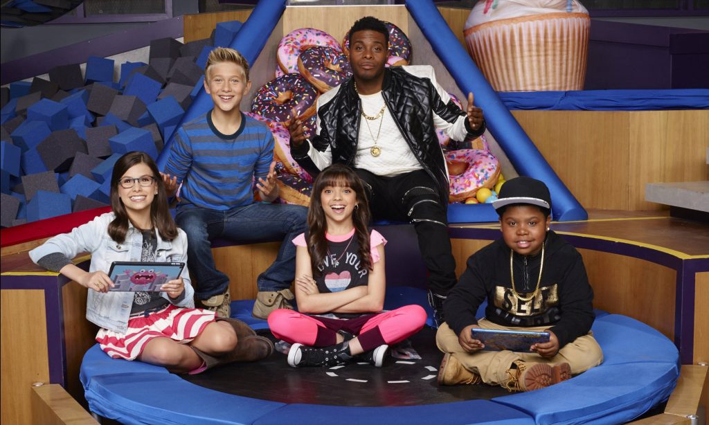 Game Shakers cast poses in vibrant studio with giant donut props bright fun wallpaper background