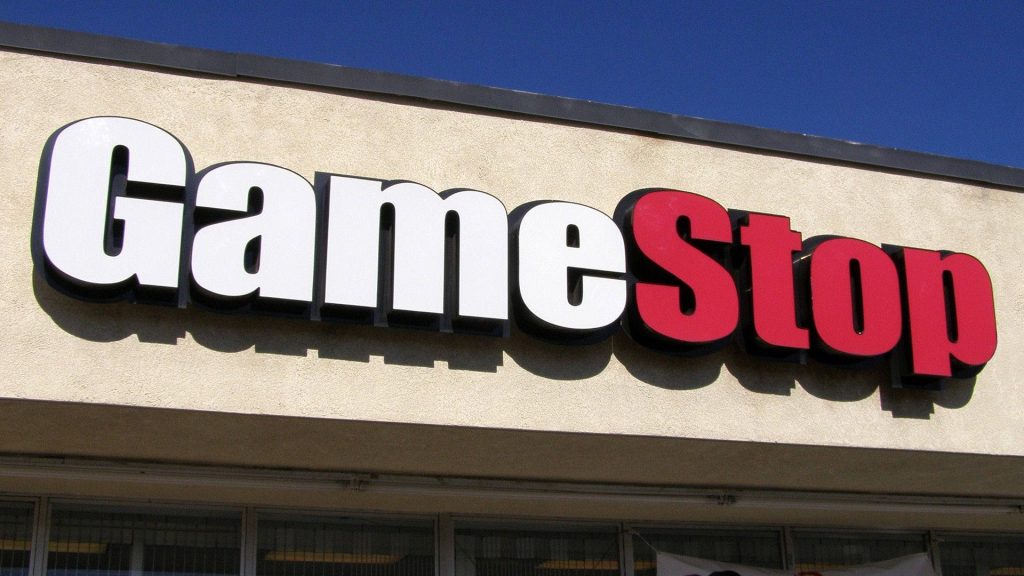 GameStop store exterior with bold red white 3D logo on beige wall under clear blue sky Wallpaper