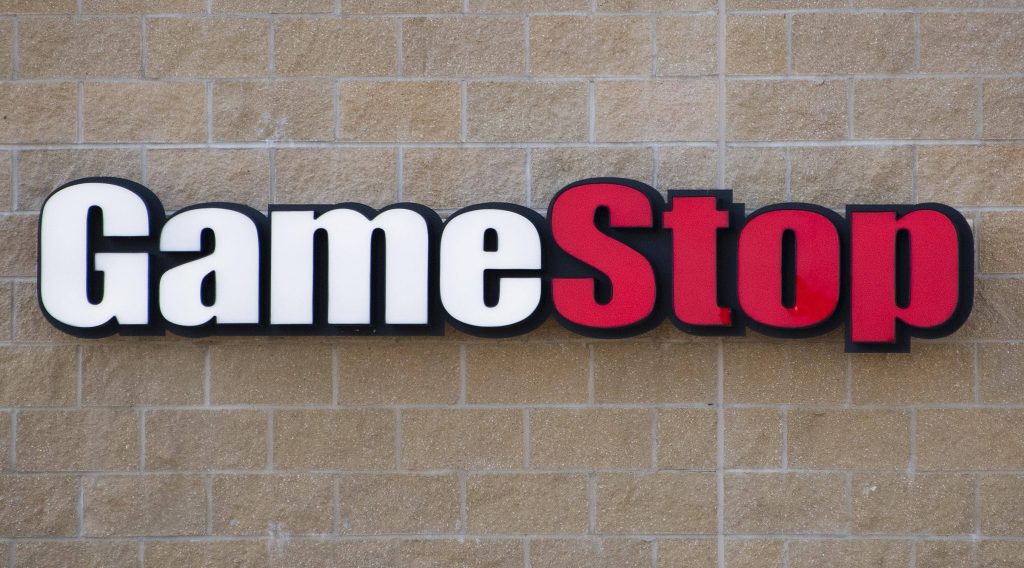 GameStop sign on textured tan brick wall bold white red black lettering retail logo Wallpaper