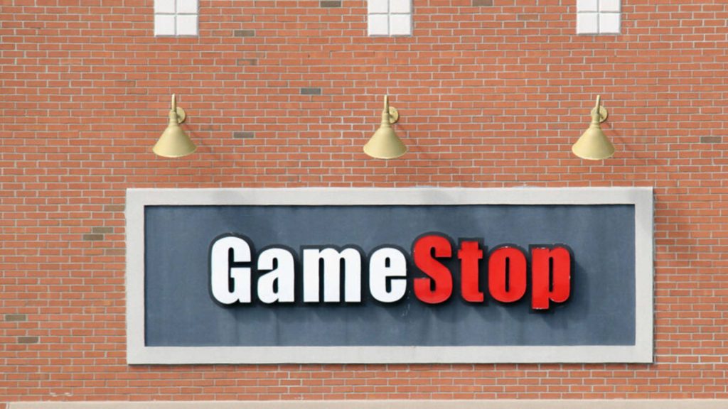 GameStop logo on orange brick wall with overhead lights for gamer screen wallpaper background